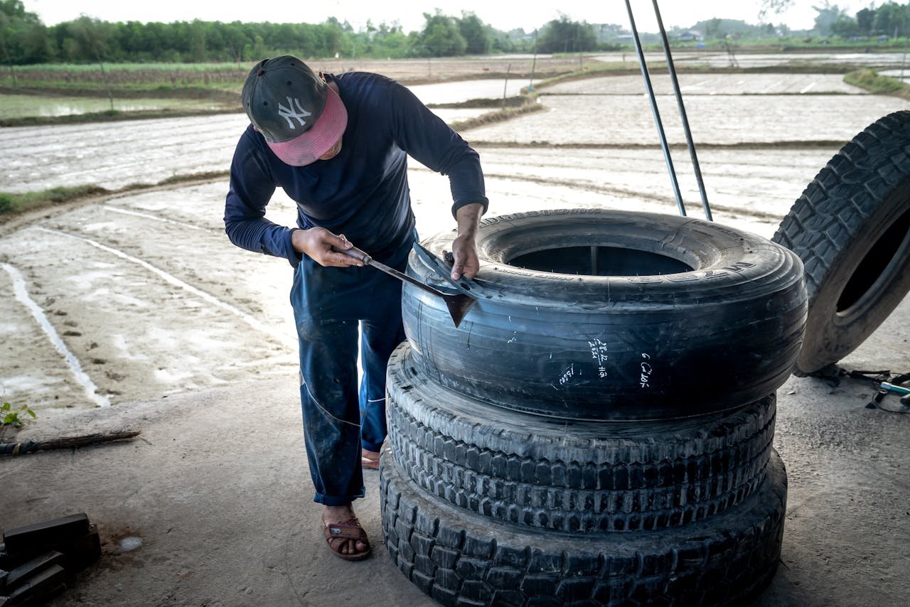 The Art of Drawing Readers In: Your attractive post title goes here Mechanic working on large tires in an outdoor rural setting, showcasing hands-on craftsmanship.