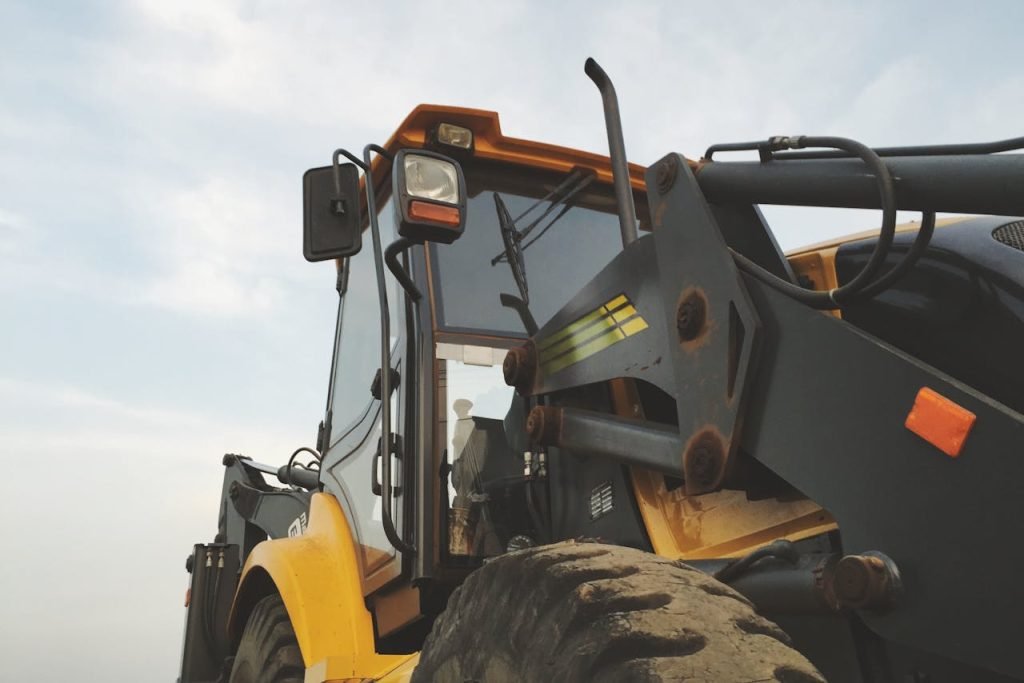 Inicio Detailed view of a yellow excavator against a clear sky at a construction site.